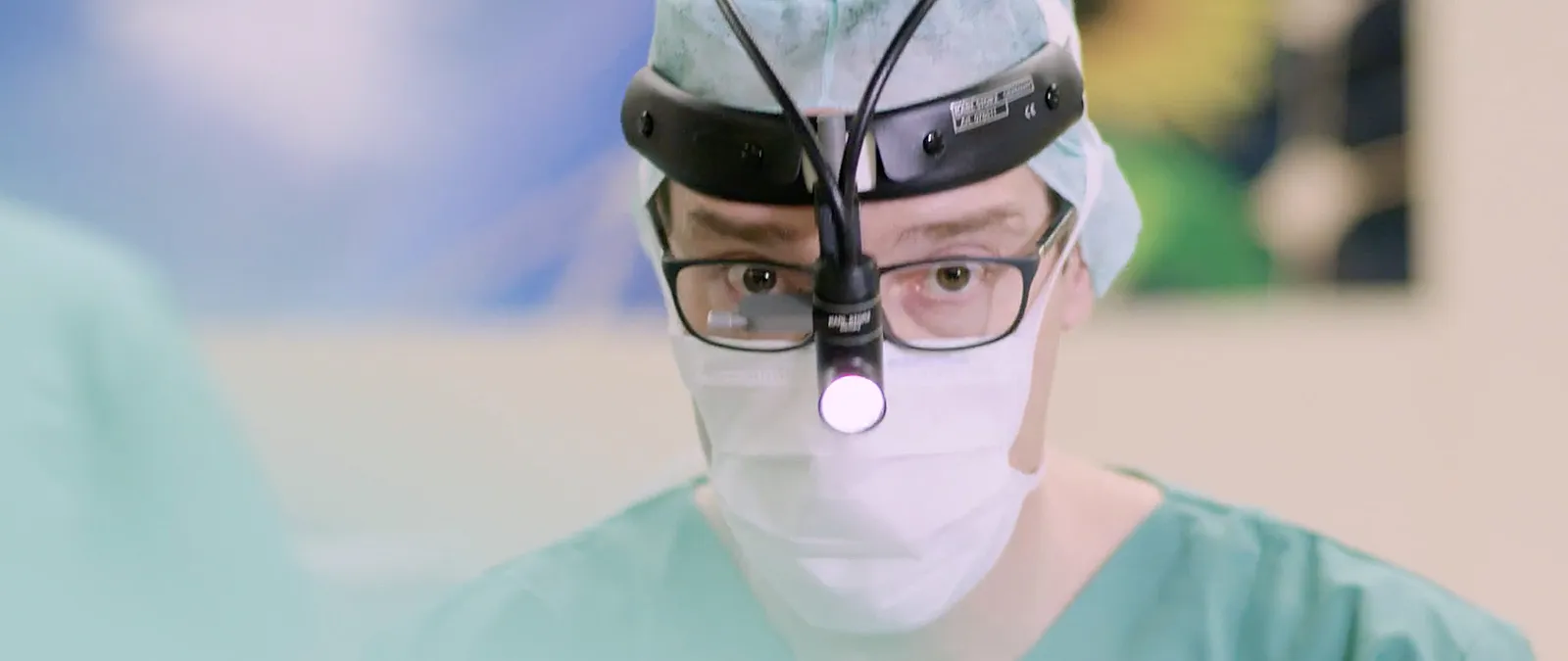 Chirurg aus Imagefilm mit Stirnlampe und Mundschutz in Nahaufnahme