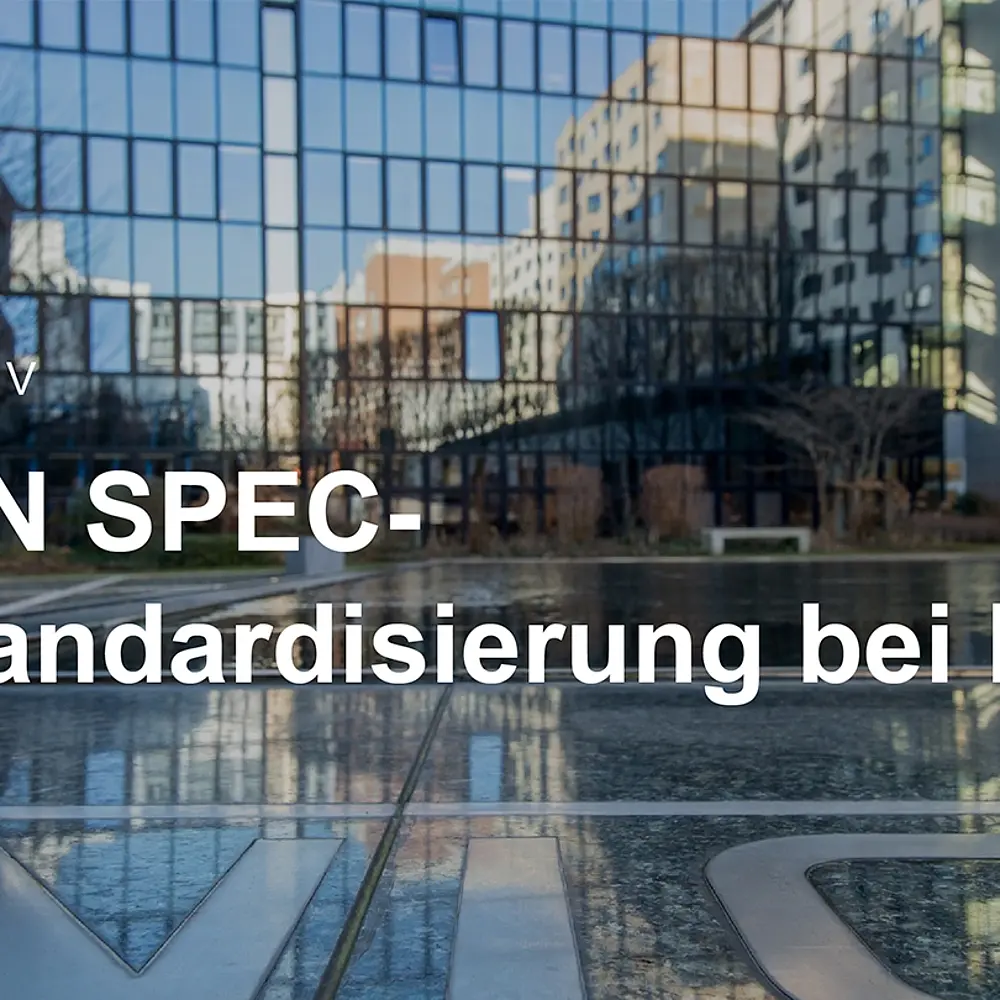 Text : DIN SPEC - Standardisierung bei DIN und im Hintergrund ein öffentlicher Platz