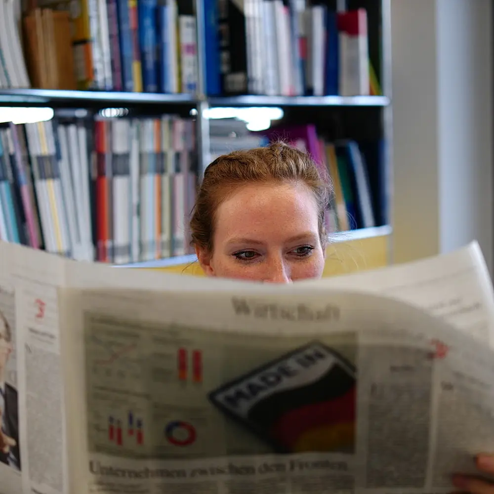 Frau, die den Wirtschaftsteil der Printausgabe einer Zeitung liest