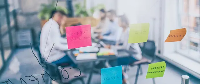 Foto mit Menschen am Tisch, die gemeinsam Brainstorming betreiben