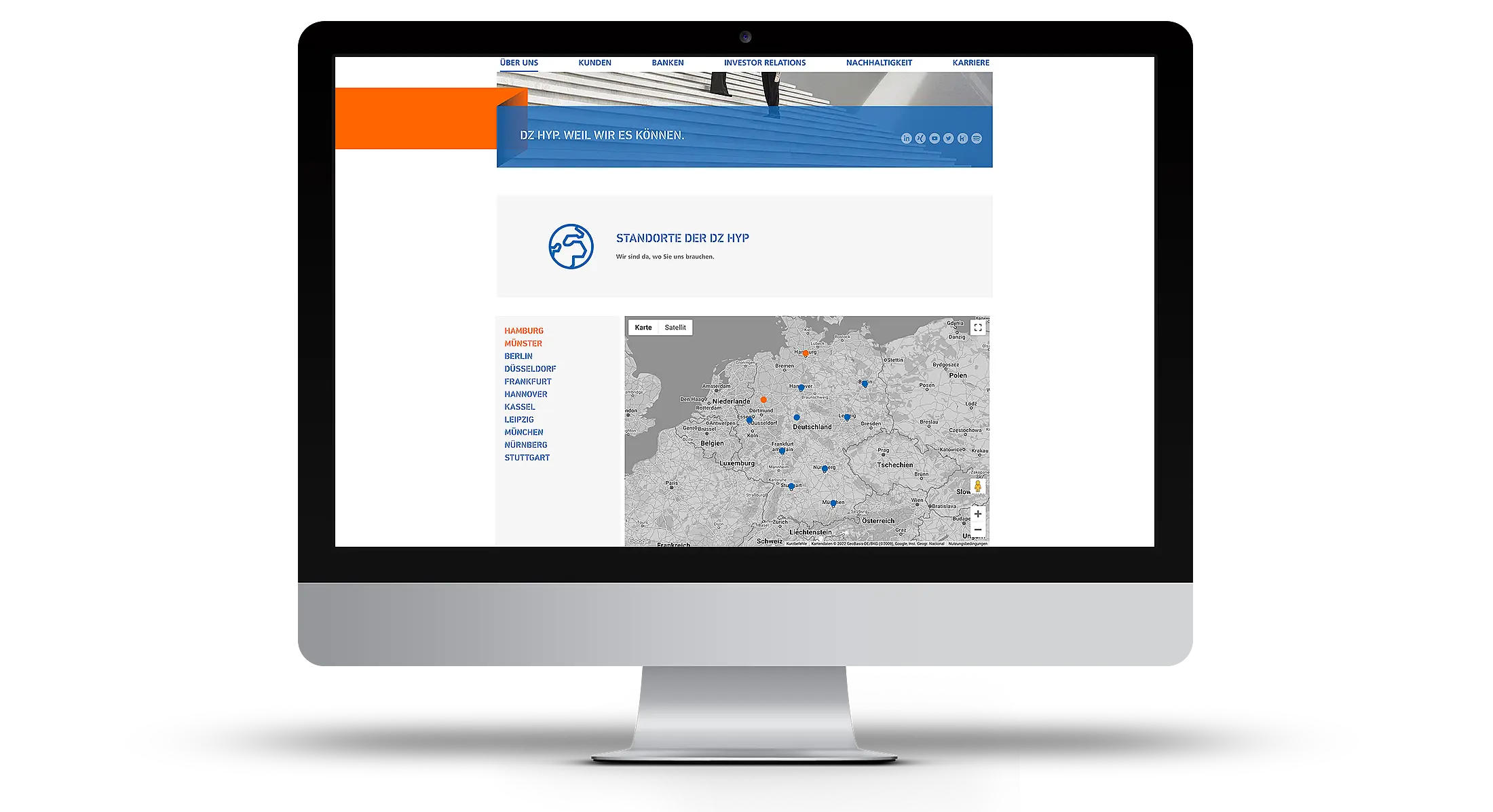 Desktop-Monitor mit geöffneter DZ-HYP-Website auf hellem grauen Hintergrund.