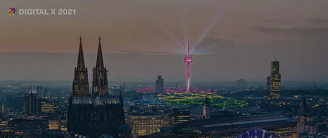 Foto von Köln mit Dom und Fernsehturm in der Dämmerung. Der Fernsehturm ist pink gefärbt und über die Dächer der Stadt sind bunte Netzwerklinien eingezeichnet