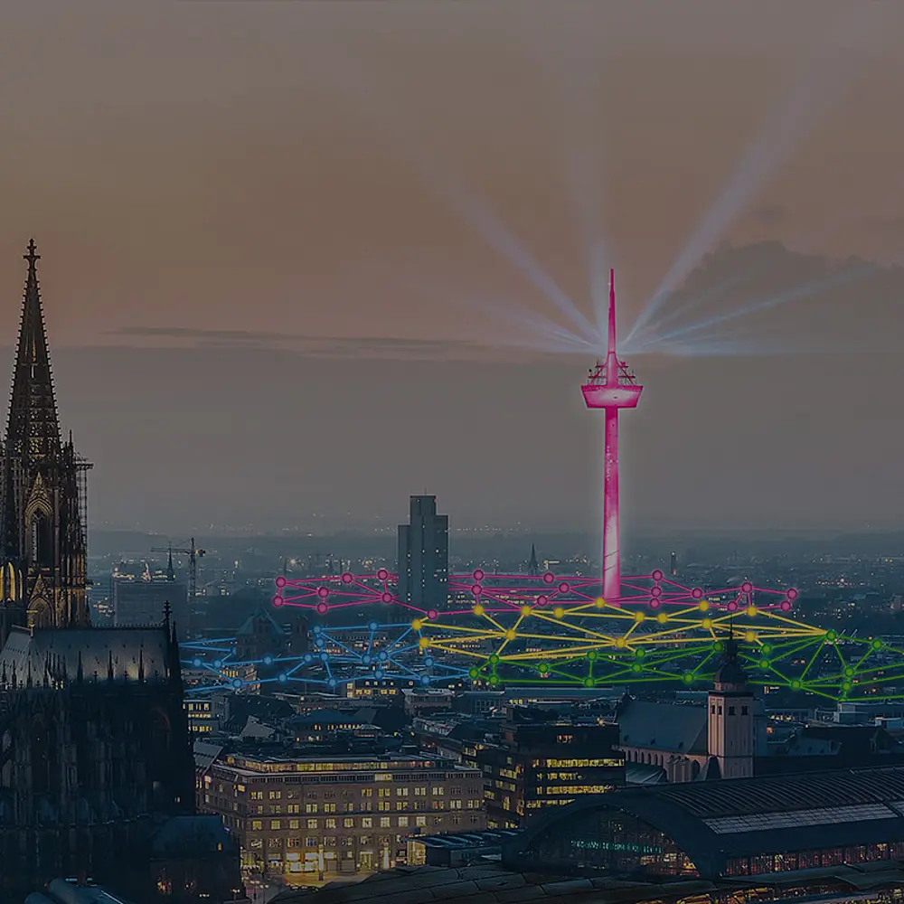 Foto von Köln mit Dom und Fernsehturm in der Dämmerung. Der Fernsehturm ist pink gefärbt und über die Dächer der Stadt sind bunte Netzwerklinien eingezeichnet
