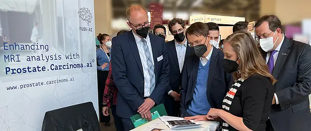 Gesundheitsminister Lauterbach steht mit Dr. Sabrina Reimers-Kipping zusammen an dem Messestand von FUSE-AI