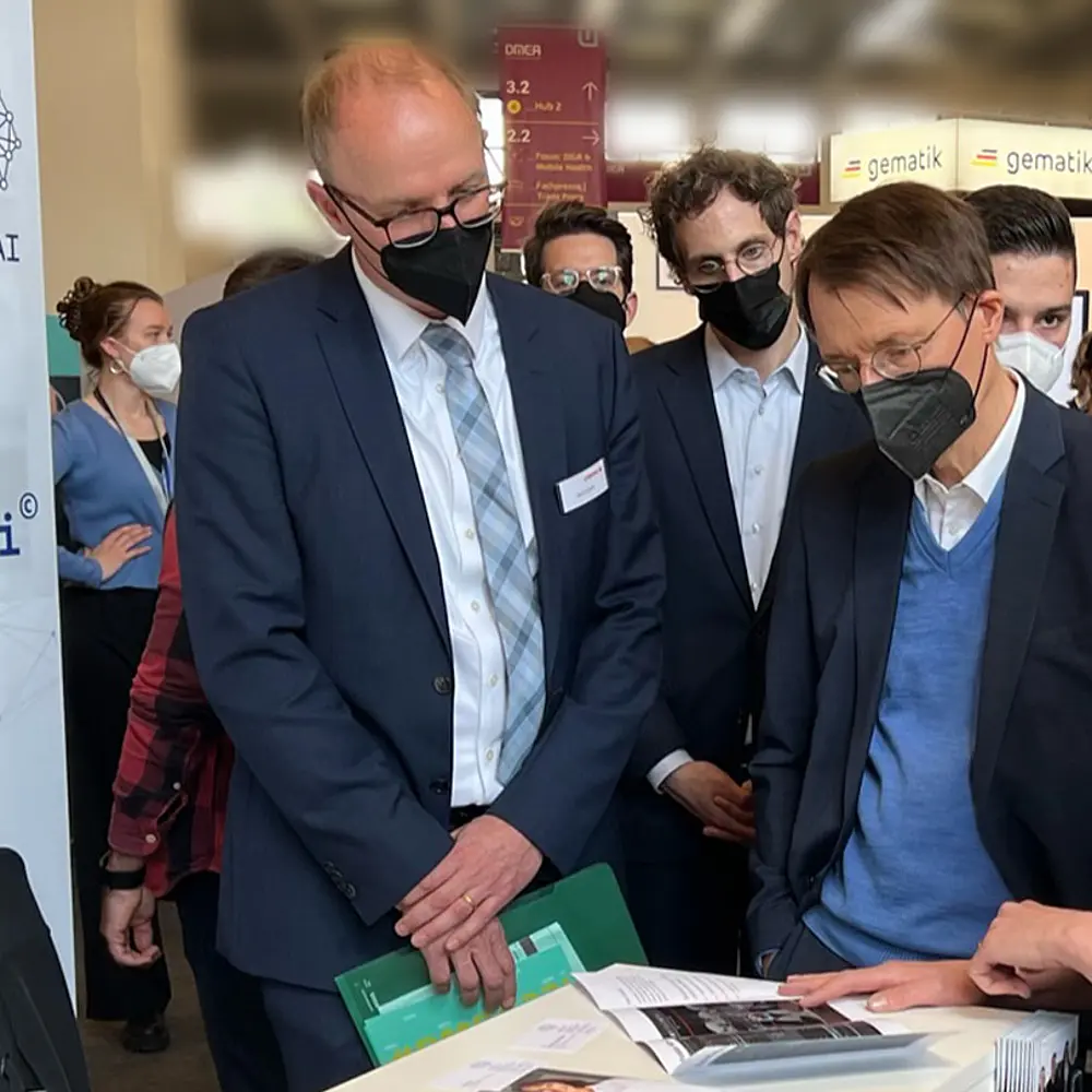 Gesundheitsminister Lauterbach steht mit Dr. Sabrina Reimers-Kipping zusammen an dem Messestand von FUSE-AI