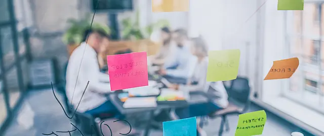 Durch einen Glasscheibe hindurch fotografierte Brainstorming- Szene