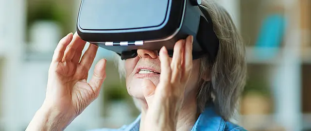Alte Frau guckt in VR-Brille