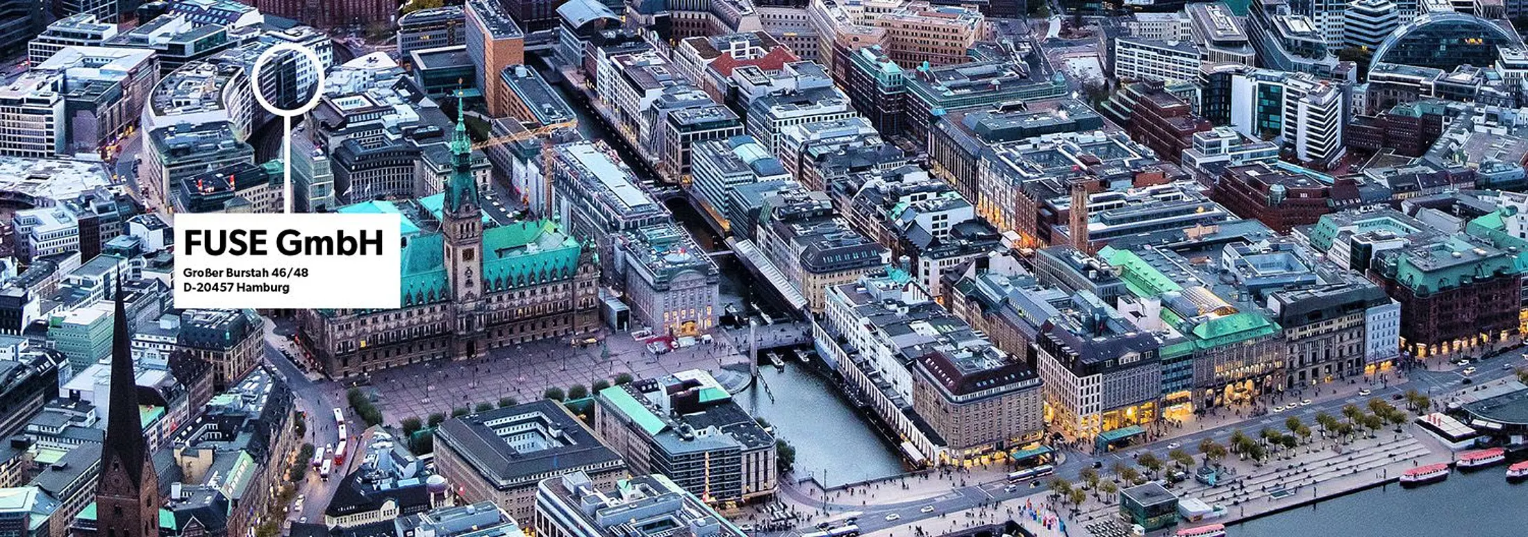 Luftaufnahme der Hamburger Innenstadt mit Rathaus, Binnenalster und umliegenden Gebäuden. Eine Markierung hebt den Standort der FUSE GmbH am Großen Burstah 46/48 in Hamburg hervor.