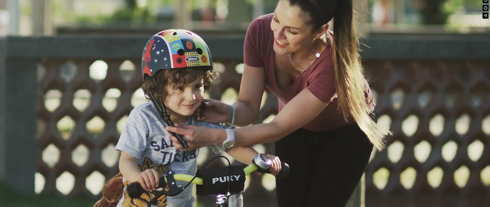 Mutter und Kind mit Fahrradhelm beim Anlegen des Kinnriemens für Imagefilm