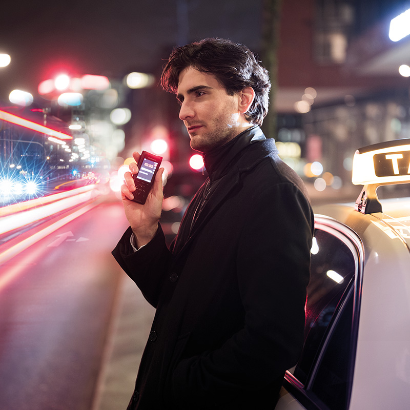 Person hält einen Olympus Audiorekorder in nächtlicher Straßenszene