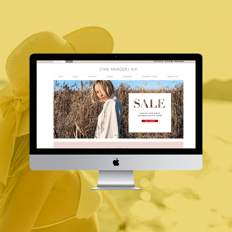 Onlineshop von The Mercer N.Y. auf einem Desktop-Monitor mit großem Sale-Banner vor gelb getöntem Fashion-Hintergrund.